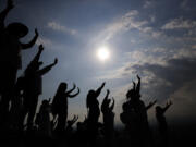 FILE - Visitors hold their hands out to receive the sun's energy as they celebrate the Spring equinox atop the Pyramid of the Sun in Teotihuacan, Mexico, Thursday, March 21, 2019. Spring gets its official start Tuesday, March 19, 2024, in the Northern Hemisphere. On the equinoxes, the Earth's axis and orbit line up so both hemispheres get the same amount of sunlight.