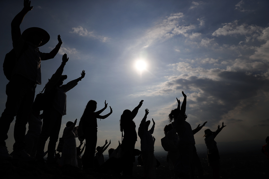 FILE - Visitors hold their hands out to receive the sun's energy as they celebrate the Spring equinox atop the Pyramid of the Sun in Teotihuacan, Mexico, Thursday, March 21, 2019. Spring gets its official start Tuesday, March 19, 2024, in the Northern Hemisphere. On the equinoxes, the Earth's axis and orbit line up so both hemispheres get the same amount of sunlight.