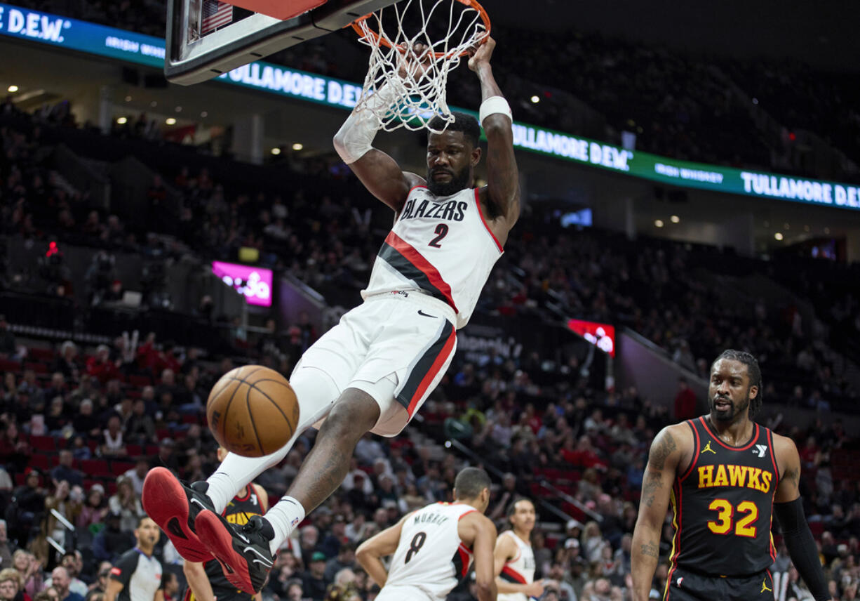 Portland Trail Blazers center Deandre Ayton, left, dunks in front of Atlanta Hawks guard Wesley Matthews during the second half of an NBA basketball game in Portland, Ore., Wednesday, March 13, 2024.