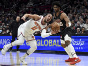 New York Knicks guard Jalen Brunson, left, drives to the basket against Portland Trail Blazers guard Scoot Henderson, right, during the first half of an NBA basketball game in Portland, Ore., Thursday, March 14, 2024.