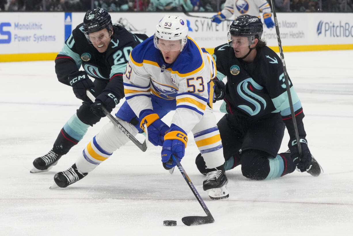 Buffalo Sabres left wing Jeff Skinner (53) reaches for the puck while pursued by Seattle Kraken right wing Eeli Tolvanen, left, and defenseman Will Borgen, right, during the second period of an NHL hockey game Monday, March 18, 2024, in Seattle.
