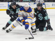 Buffalo Sabres left wing Jeff Skinner (53) reaches for the puck while pursued by Seattle Kraken right wing Eeli Tolvanen, left, and defenseman Will Borgen, right, during the second period of an NHL hockey game Monday, March 18, 2024, in Seattle.