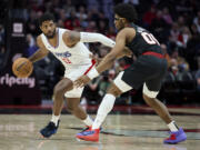 Los Angeles Clippers forward Paul George, left, dribbles the ball around Portland Trail Blazers guard Scoot Henderson during the second half of an NBA basketball game in Portland, Ore., Wednesday, March 20, 2024.