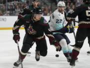 Arizona Coyotes left wing John Leonard (49) drops the puck in front of Seattle Kraken right wing Oliver Bjorkstrand (22) in the second period during an NHL hockey game, Friday, March 22, 2024, in Tempe, Ariz.
