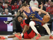 Portland Trail Blazers guard Ashton Hagans, left, and Denver Nuggets guard Collin Gillespie (21) scramble for a loose ball during the second half of an NBA basketball game Saturday, March 23, 2024, in Portland, Ore.