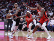 Portland Trail Blazers forward Jabari Walker, left, drives to the basket around Houston Rockets guard Aaron Holiday (0) forward Reggie Bullock Jr., right, during the first half of an NBA basketball game, Monday, March 25, 2024, in Houston.