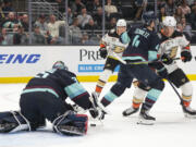 Seattle Kraken goaltender Joey Daccord (35) covers the puck and defenseman Justin Schultz (4) defends as Anaheim Ducks center Ryan Strome (16) moves in during the second period of an NHL hockey game Tuesday, March 26, 2024, in Seattle.