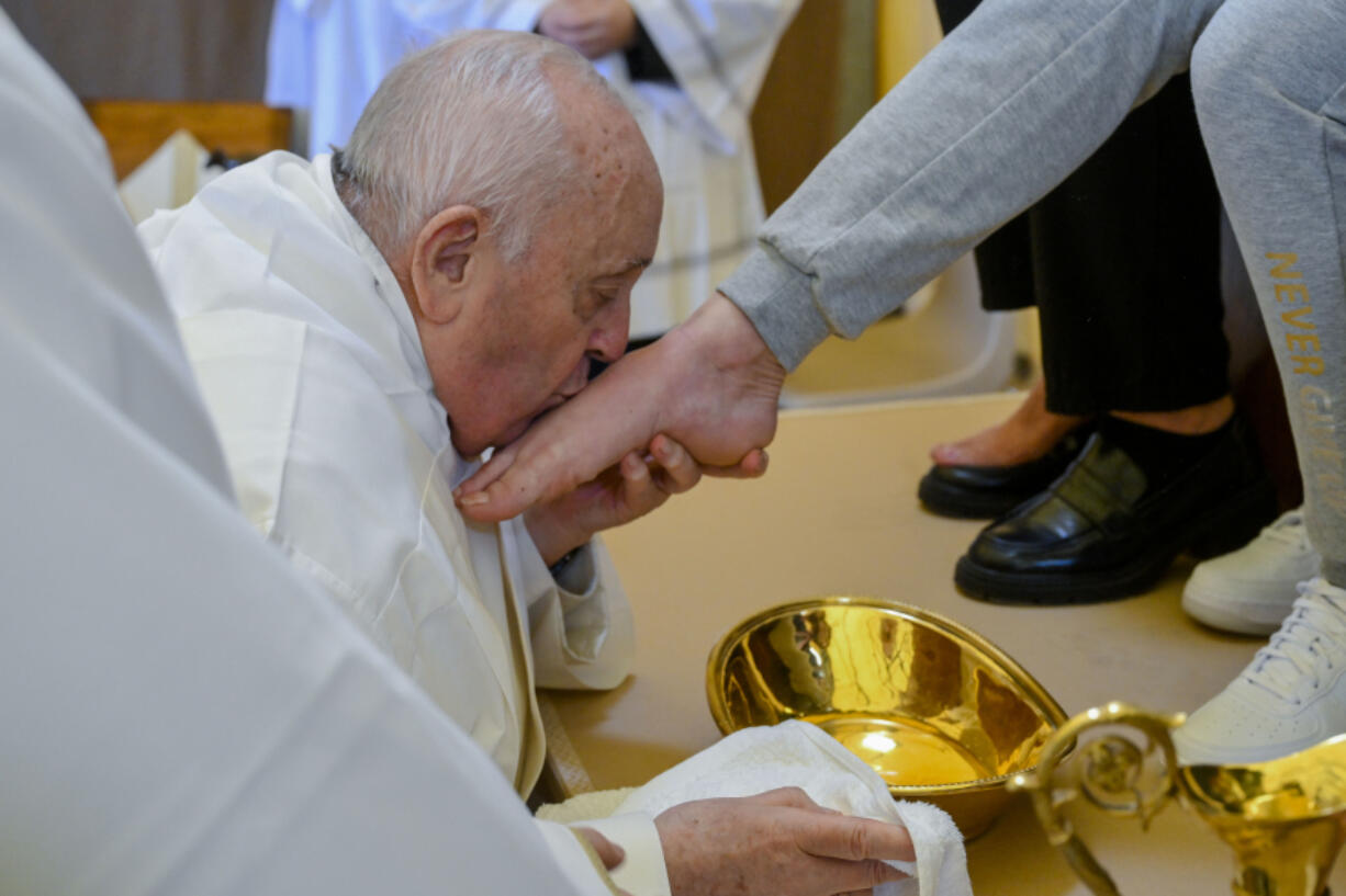 In this image made available by Vatican Media, Pope Francis kisses the foot of a woman inmate of the Rebibbia prison on the outskirts of Rome on Holy Thursday, March 28, 2024, a ritual meant to emphasize his vocation of service and humility. The Holy Thursday foot-washing ceremony is a hallmark of every Holy Week and recalls the foot-washing Jesus performed on his 12 apostles at their last supper together before he was crucified.