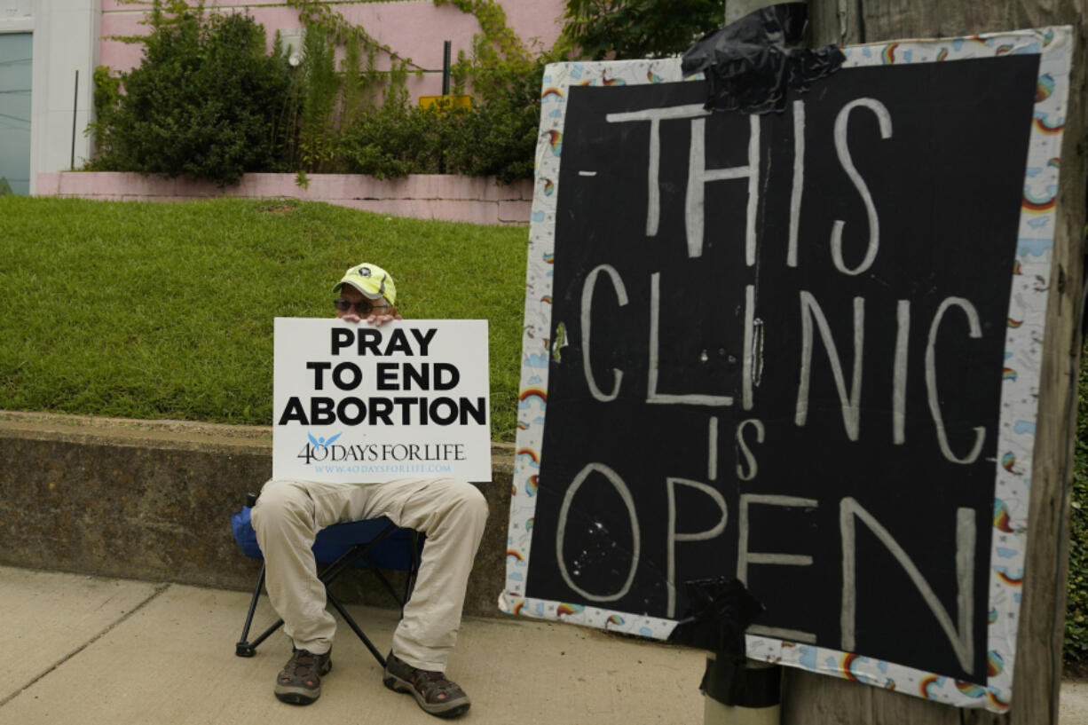 FILE - An anti-abortion supporter sits behind a sign that advises the Jackson Women&#039;s Health Organization clinic is still open in Jackson, Miss., July 6, 2022.  A report finds the total number of monthly abortions in the U.S. increased after state bans started kicking in in 2022. (AP Photo/Rogelio V.