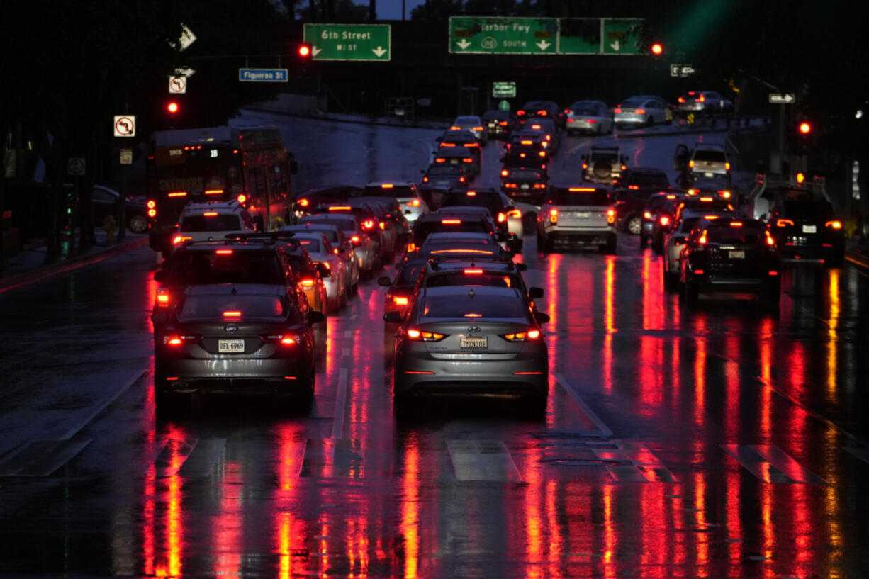 FILE - Car lights are reflected in the wet street as commuters line up in traffic to enter the I-110 Harbor freeway in the rain in downtown Los Angeles,  March 6, 2024. Most electronic systems that take on some driving tasks for humans don&rsquo;t adequately make sure drivers are paying attention, and they don&rsquo;t issue strong enough warnings to make drivers behave. That&rsquo;s according to an insurance industry study published Tuesday, March 12, 2024.