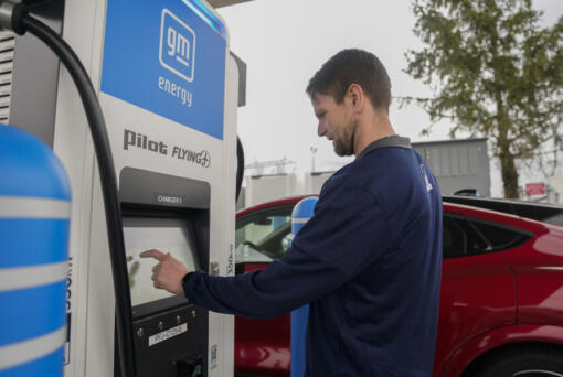 Liam Sawyer, of Indianapolis, touches the screen as he charges his 2023 Ford Mustang Mach-E, Friday, March 8, 2024, at an electric vehicle charging station in London, Ohio. The charging ports are a key part of President Joe Biden&rsquo;s effort to encourage drivers to move away from gasoline-powered cars and trucks that contribute to global warming. (AP Photo/Joshua A.