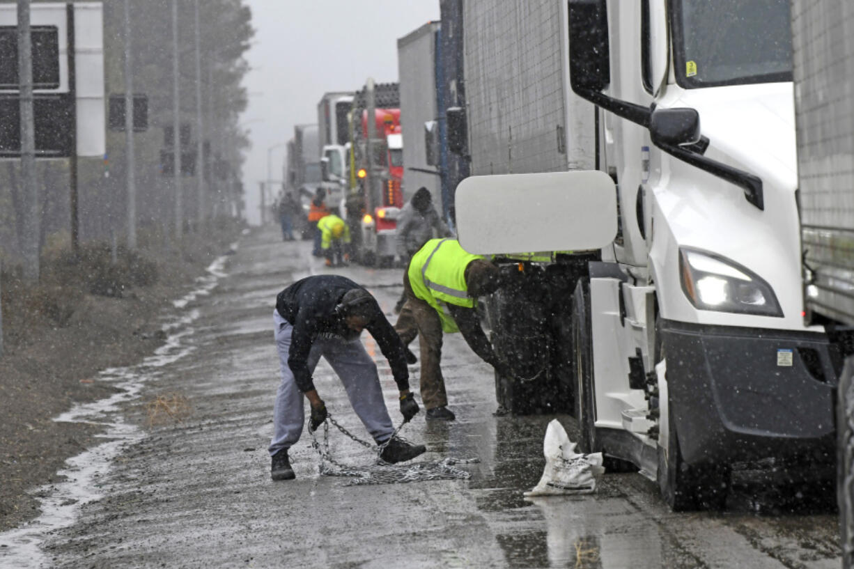 A long line of trucks are parked off the west bound I-80 as drivers put chains on the truck wheels in preparation for the snow storm over the Sierra Nevada on Thursday, Feb. 29, 2024, in Lake Tahoe, Calif.