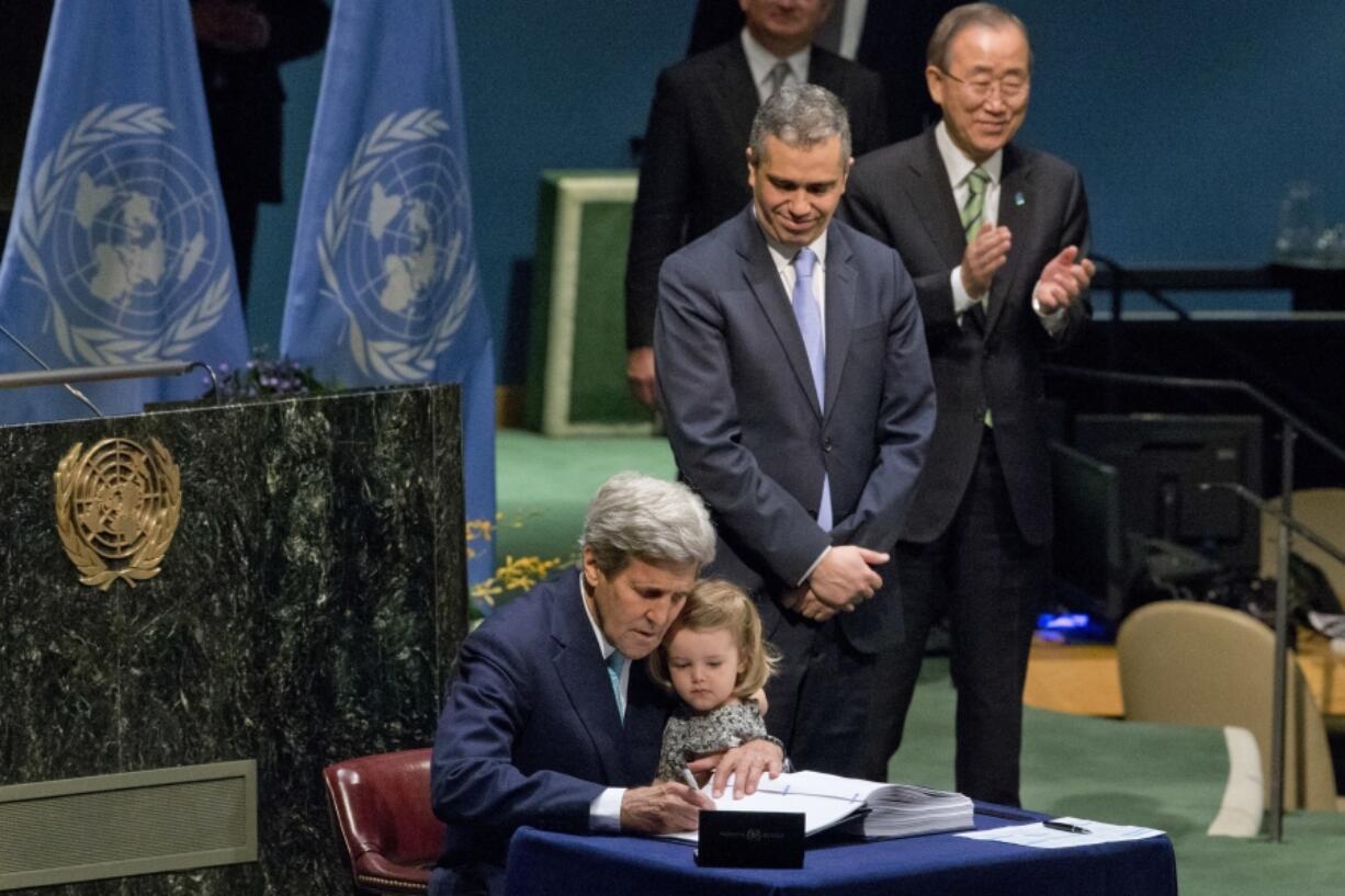 FILE - U.S. Secretary of State John Kerry holds his granddaughter as he signs the Paris Agreement on climate change, April 22, 2016 at U.N. headquarters.