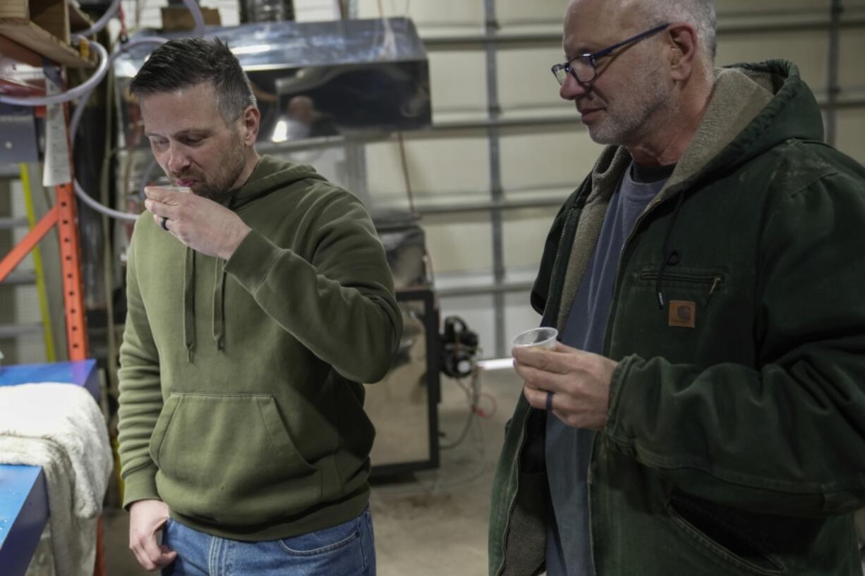 Jonathan Davis, left, tastes the first run of maple syrup with his father, Steven, right, Saturday, Feb. 24, 2024, in Sturgeon Bay, Wis. Steven Davis, who started tapping 220 trees on his family&rsquo;s land about six years ago, said he now feels &ldquo;more like partners&rdquo; with the land. (AP Photo/Joshua A.