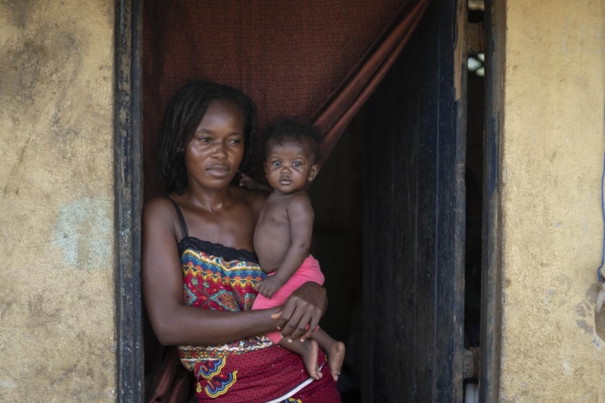 Annie Kopacitino holds her daughter, who she says has been affected by the pollution caused by oil drilling, in her village of Tshiende, Moanda, Democratic Republic of the Congo, Saturday, Dec. 23, 2023. The country is looking to expand the oil drilling.