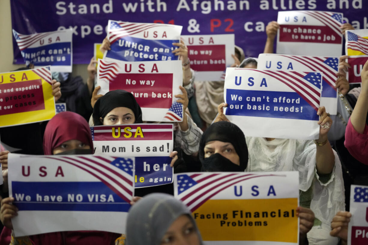FILE - Afghan refugees hold placards during a gathering in Islamabad, Pakistan, July 21, 2023. Senators from both parties are urging congressional leaders to ensure that more visas are made available to Afghans who worked alongside U.S. troops in America&rsquo;s longest war. The senators say an additional 20,000 visas are needed before the end of the fiscal year in September.