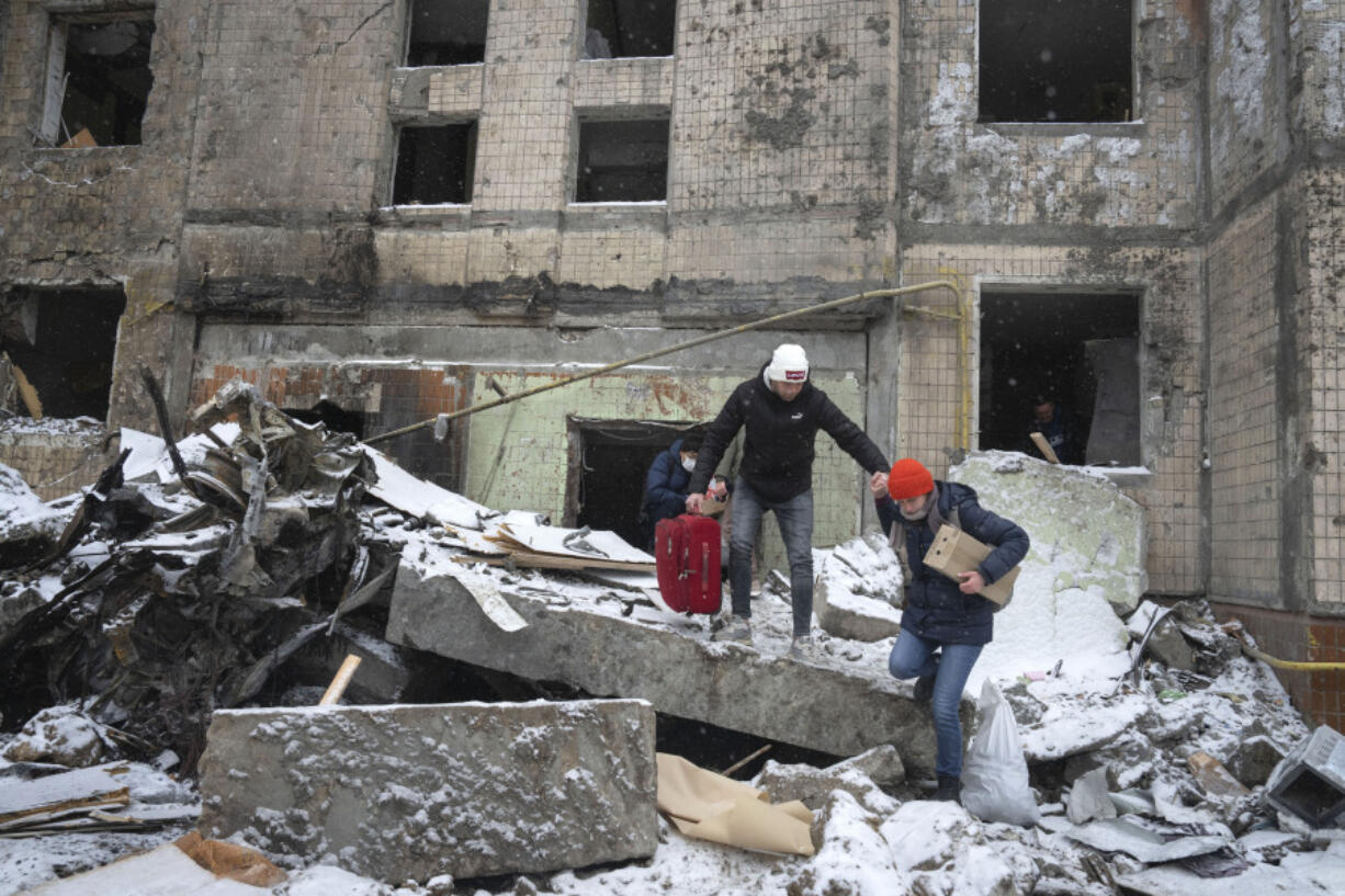 FILE - People walk with belongings out from an apartment building destroyed after Tuesday&rsquo;s Russian attack in Kyiv, Ukraine, Jan. 3, 2024. House Democrats on Tuesday, March 12, 2024, launched a long-shot effort to push $95 billion in aid for Ukraine, Israel and Taiwan to a vote. The move ramps up pressure on House Speaker Mike Johnson to take up the foreign funding package.