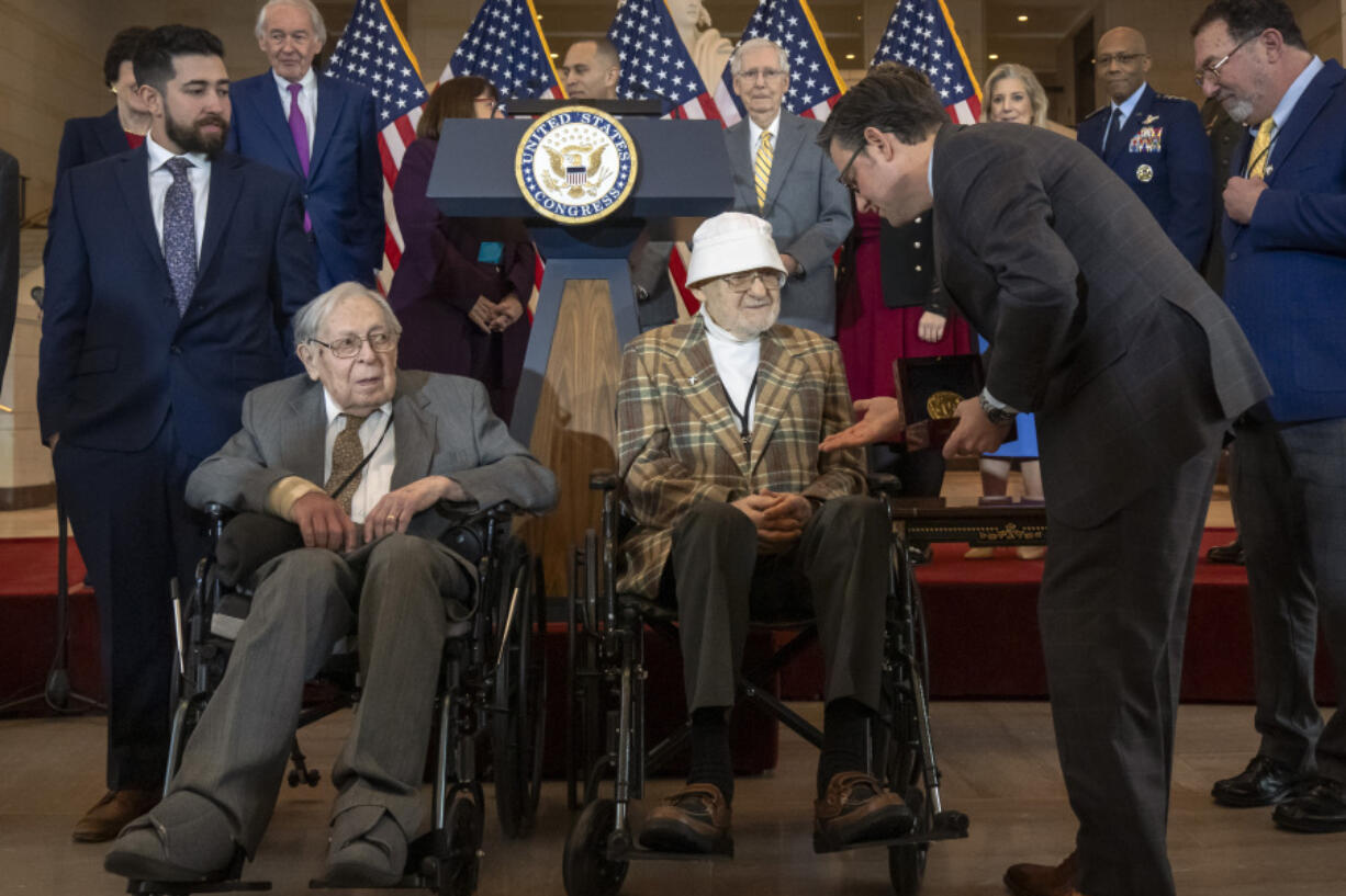 House Speaker Mike Johnson, R-La., right, presents Ghost Army member Bernard Bluestein, of Hoffman Estates, Ill., with a medal during a ceremony to honor members of the secretive WWII-era unit with the Congressional Gold Medal during a ceremony on Capitol Hill, Thursday, March 21, 2024, in Washington. At left is fellow Ghost Army member Seymour Nussenbaum of Monroe Township, N.J.