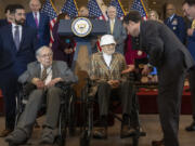 House Speaker Mike Johnson, R-La., right, presents Ghost Army member Bernard Bluestein, of Hoffman Estates, Ill., with a medal during a ceremony to honor members of the secretive WWII-era unit with the Congressional Gold Medal during a ceremony on Capitol Hill, Thursday, March 21, 2024, in Washington. At left is fellow Ghost Army member Seymour Nussenbaum of Monroe Township, N.J.