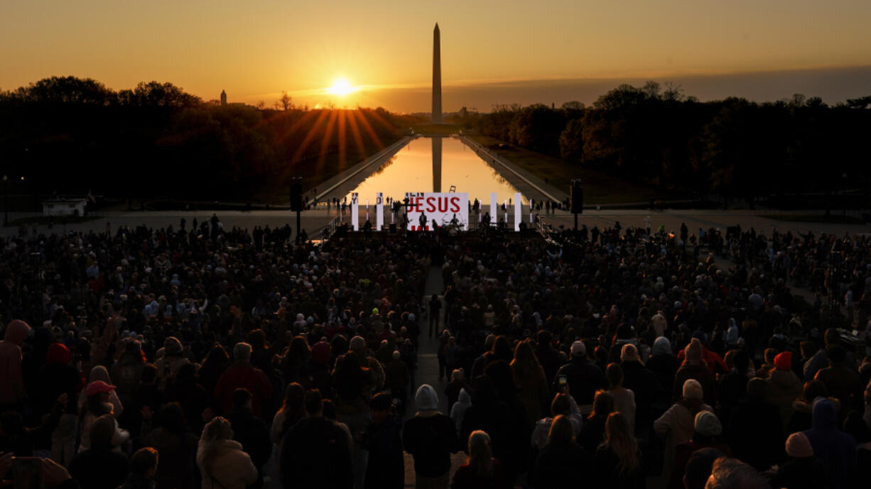 FILE -  The word &ldquo;Jesus&rdquo; is displayed on a large monitor and worship songs are played on stage as people gather for the &ldquo;Easter Sunrise Service&rdquo; at the Lincoln Memorial, Sunday, April 9, 2023, in Washington, hosted by the National Community Church. On Easter morning, many Christians wake before dawn. They will celebrate their belief in the resurrection of Jesus, the son of God, as the sun rises.