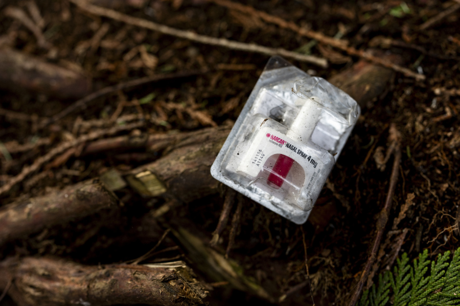 A container of Narcan, or naloxone, sits on tree roots at a longstanding homeless encampment.