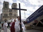 A priest holds a cross during a Good Friday ceremony outside Notre Dame cathedral , as part of Easter celebrations, Friday, March 29, 2024 in Paris.