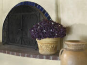 This image provided by Proven Winners shows a Charmed Wine shamrock plant in bloom beside a fireplace.