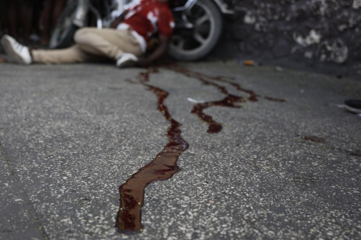 The body of a man lies in a pool of blood alongside his motorcycle, in the Delmas area of Port-au-Prince, Haiti, Friday, March 8, 2024. Witnesses say he was shot by two unidentified men on motorcycles.