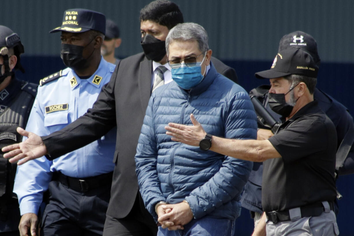 FILE - Former Honduran President Juan Orlando Hernandez, second from right, is taken in handcuffs to a waiting aircraft as he is extradited to the United States, at an Air Force base in Tegucigalpa, Honduras, April 21, 2022. Hern&aacute;ndez has been convicted in New York, Friday, March 8,  of charges that he conspired with drug traffickers, his military and police to enable tons of cocaine to make it unhindered into the United States.