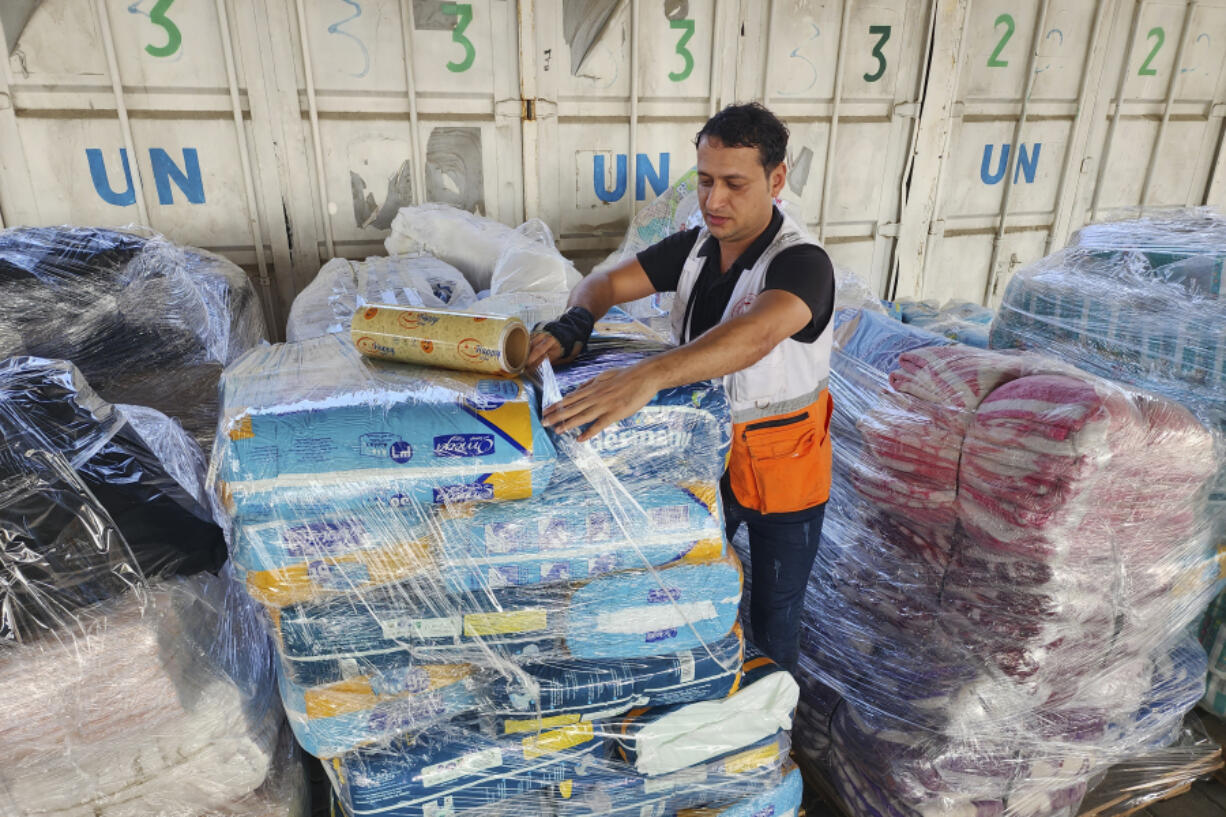 FILE - A United Nations worker prepares aid for distribution to Palestinians at UNRWA warehouse in Deir Al-Balah, Gaza Strip, on Monday, Oct. 23, 2023. The spokesperson for Israel&rsquo;s welfare ministry says it has stopped providing the documentation needed for international aid workers to renew their visas because the ministry does not have the investigative muscle to look into their potential militant affiliations.