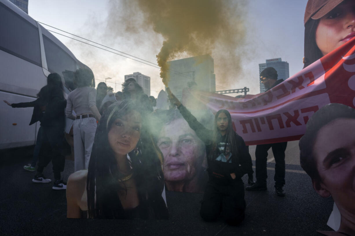 Activists block a highway while holding photos depicting the faces of Israeli women who are being held hostage in the Gaza Strip, during a protest demanding their release from Hamas captivity, in Tel Aviv, Israel, Thursday, March 14, 2024.