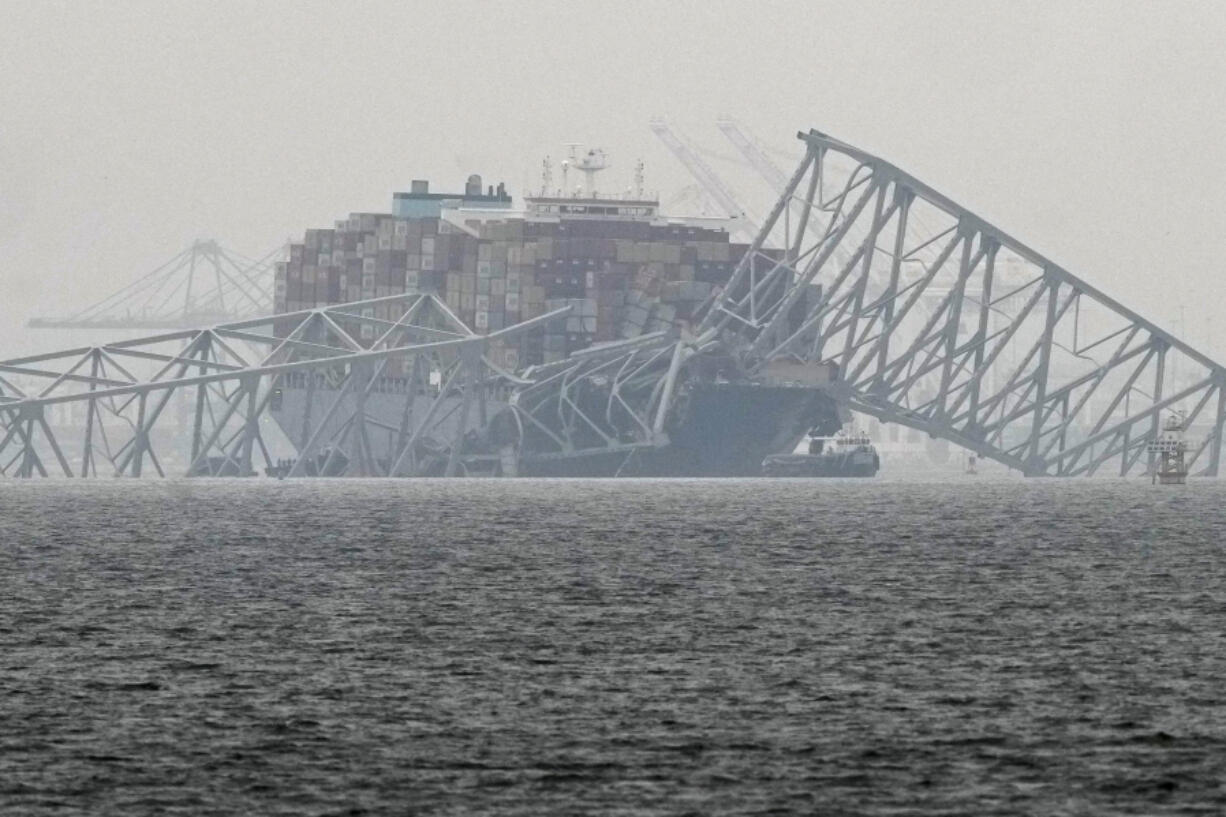 A container ship rests against the wreckage of the Francis Scott Key Bridge on Thursday, March 28, 2024, in Baltimore, Md.  After days of searching through murky water for the workers missing after the bridge collapsed, officials are turning their attention Thursday to what promises to be a massive salvage operation.