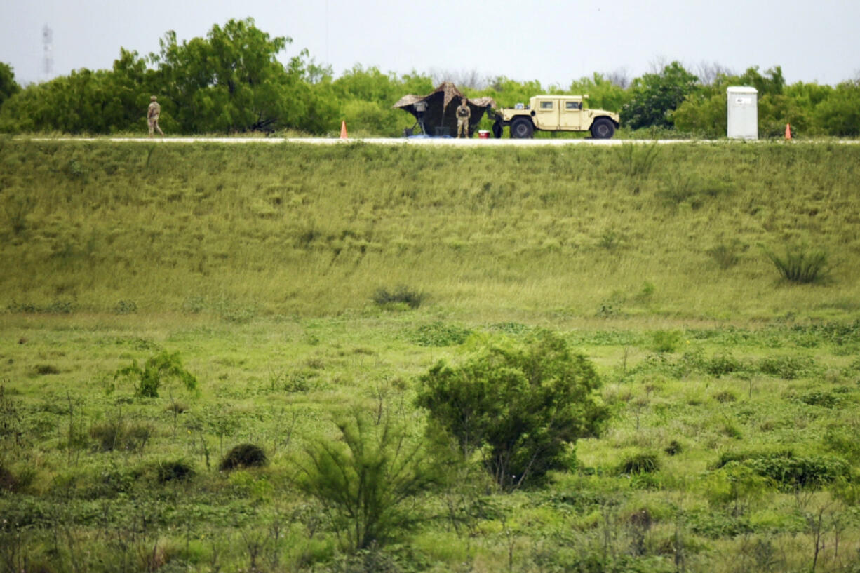 Two members of the National Guard patrol an area of land behind the federal border wall Tuesday evening, March 19, 2024, in Mission, Texas. A divided Supreme Court on Tuesday allowed Texas to begin enforcing a law that gives police broad powers to arrest migrants suspected of crossing the border illegally while a legal battle over the measure plays out.