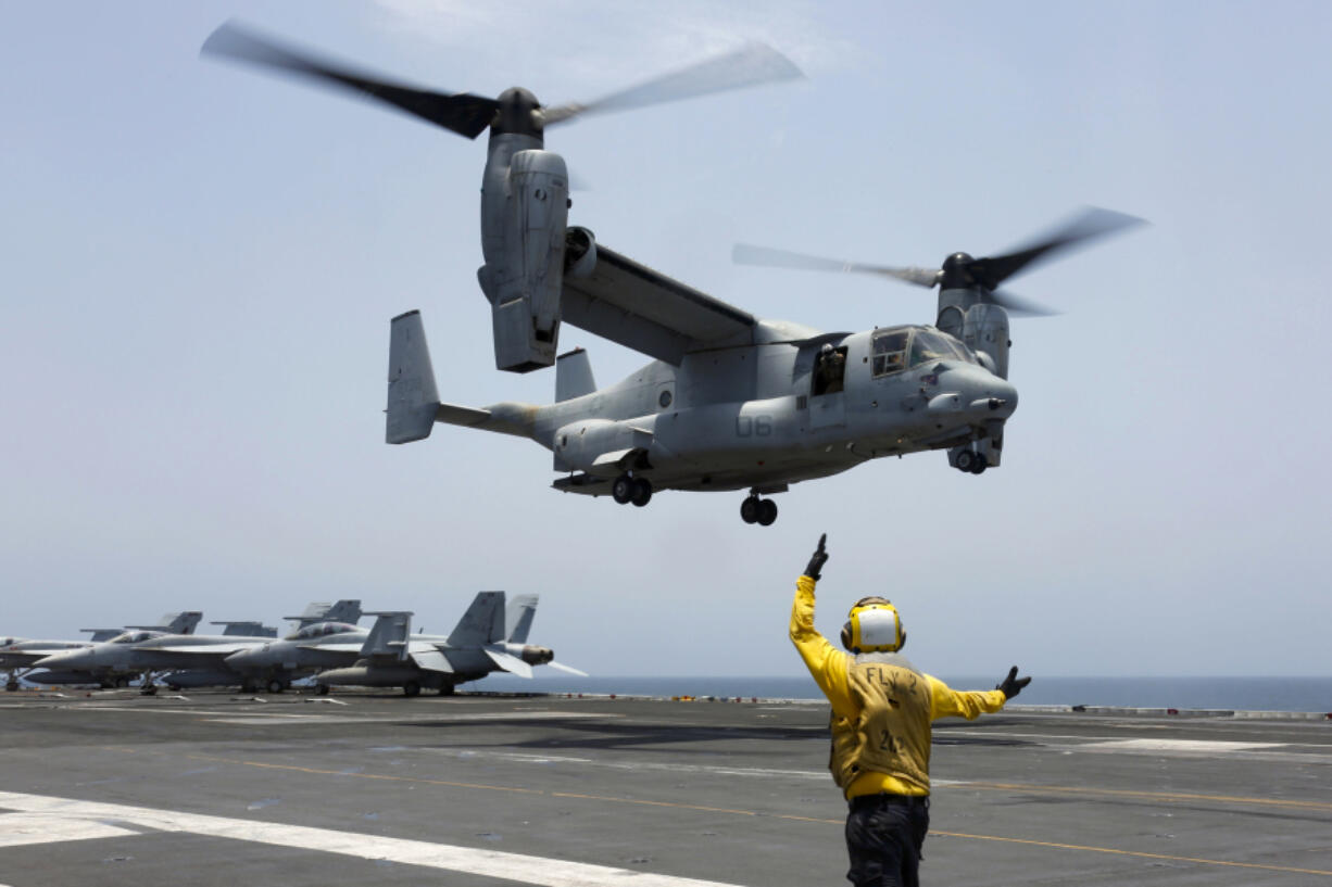 FILE -In this image provided by the U.S. Navy, Aviation Boatswain&rsquo;s Mate 2nd Class Nicholas Hawkins, signals an MV-22 Osprey to land on the flight deck of the USS Abraham Lincoln in the Arabian Sea on May 17, 2019. The military has greenlighted its Osprey to return to flight, three months after a part failure led to the deaths of eight service members in a crash in Japan in November. Naval Air Systems Command announced it on Friday.  (Mass Communication Specialist 3rd Class Amber Smalley/U.S.