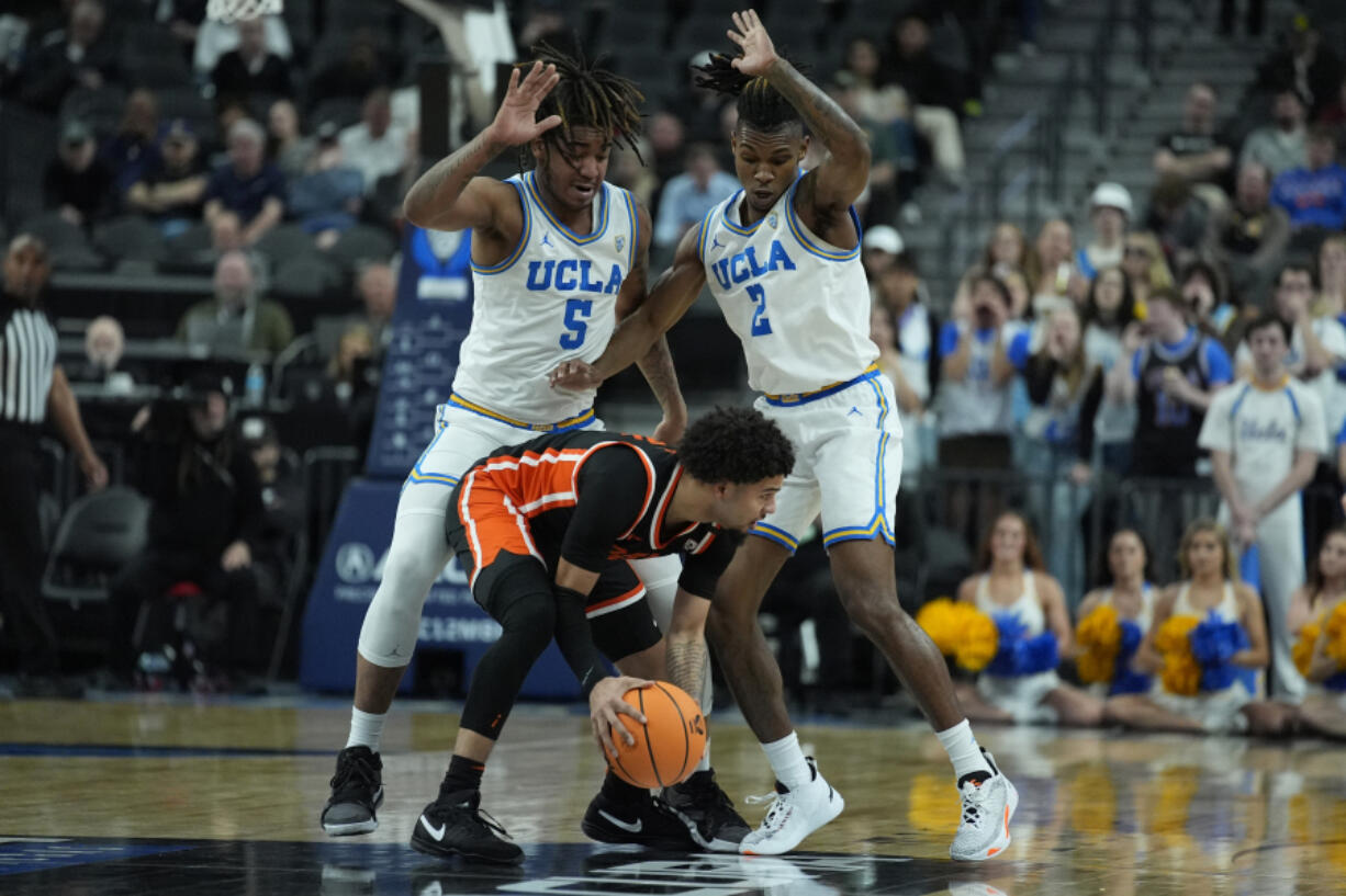 UCLA guard Brandon Williams (5) and UCLA guard Dylan Andrews (2) guard Oregon State guard Jordan Pope (0) during the first half of an NCAA college basketball game in the first round of the Pac-12 tournament Wednesday, March 13, 2024, in Las Vegas.