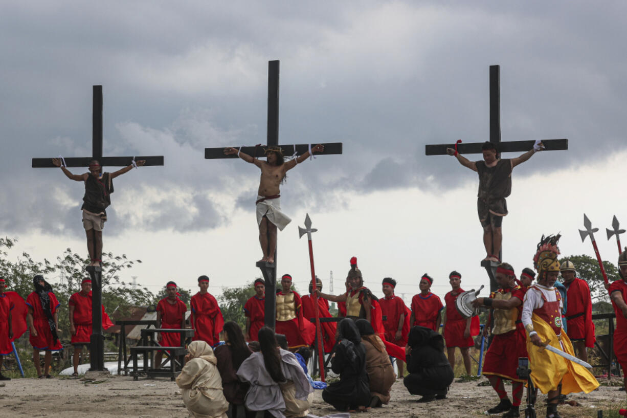 Ruben Enaje, center, remains on the cross flanked by two other devotees during the reenactment of Jesus Christ&rsquo;s sufferings as part of Good Friday rituals in San Pedro Cutud, north of Manila, Philippines, Friday, March 29, 2024. Filipino villager Ruben Enaje was nailed to a wooden cross for the 35th time to reenact Jesus Christ&rsquo;s suffering in a brutal Good Friday tradition he said he would devote to pray for peace in Ukraine, Gaza and the disputed South China Sea. (AP Photo/Gerard V.