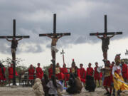 Ruben Enaje, center, remains on the cross flanked by two other devotees during the reenactment of Jesus Christ&rsquo;s sufferings as part of Good Friday rituals in San Pedro Cutud, north of Manila, Philippines, Friday, March 29, 2024. Filipino villager Ruben Enaje was nailed to a wooden cross for the 35th time to reenact Jesus Christ&rsquo;s suffering in a brutal Good Friday tradition he said he would devote to pray for peace in Ukraine, Gaza and the disputed South China Sea. (AP Photo/Gerard V.