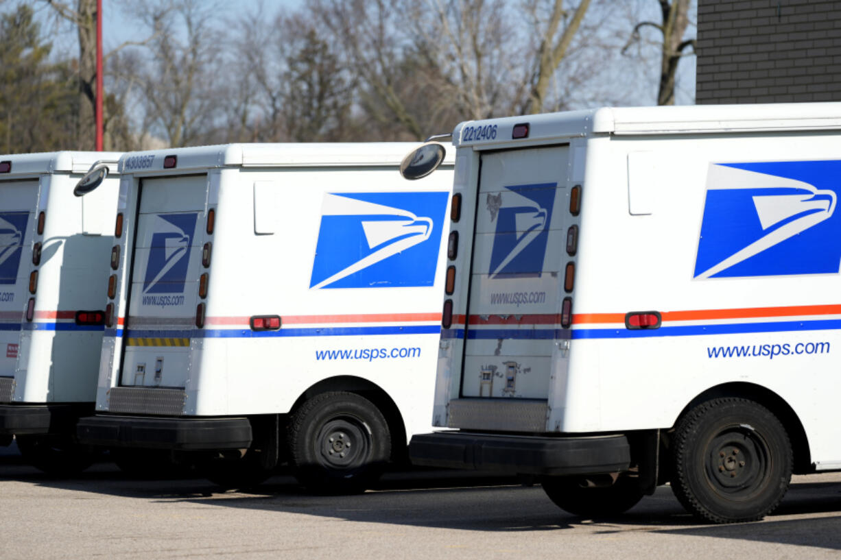 FILE - U.S. Postal Service trucks park outside a post office, Jan. 29, 2024, in Wheeling, Ill. The number of robberies of postal carriers grew again in 2023 and the number of injuries nearly doubled, even as the U.S. Postal Service launched crackdown aimed at addressing postal crime. (AP Photo/Nam Y.