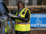 A voluntter election worker speaks with a voter during curbside early voting at the John Chavis Memorial Park Community Center, Wednesday, Feb. 21, 2024, in Raleigh, N.C.