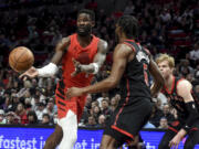 Portland Trail Blazers center Deandre Ayton, left, passes the ball as Toronto Raptors guard Immanuel Quickley, center, and guard Gradey Dick defend during the first half of an NBA basketball game in Portland, Ore., Saturday, March 9, 2024.