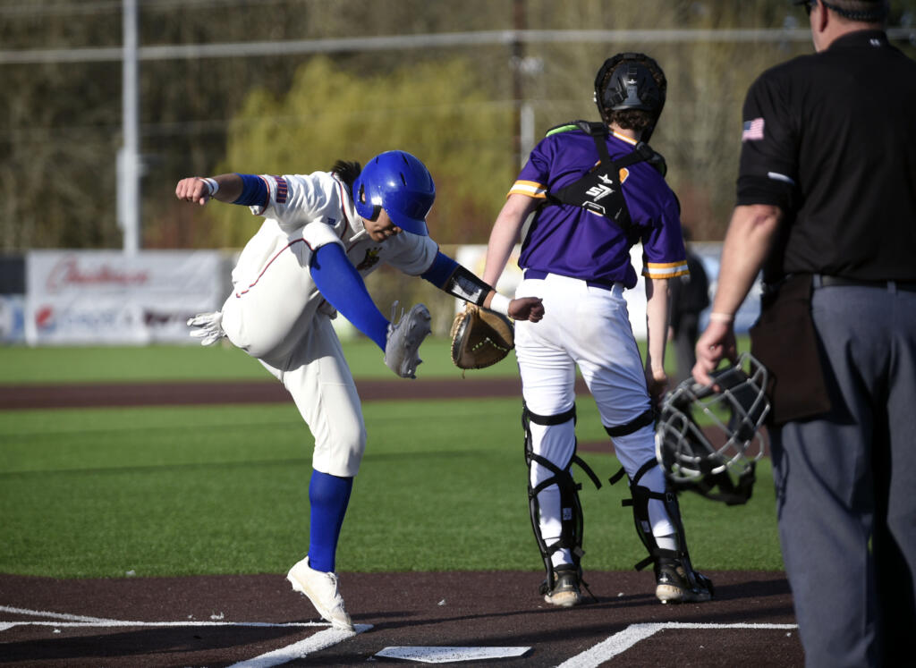 Ridgefield's Deven Savella, left, celebrates a run scored by stomping his foot at home plate during the Spudders' 2A Greater St. Helens League baseball game against Columbia River on Friday, March 29, 2024, at Ridgefield Outdoor Recreation Complex.