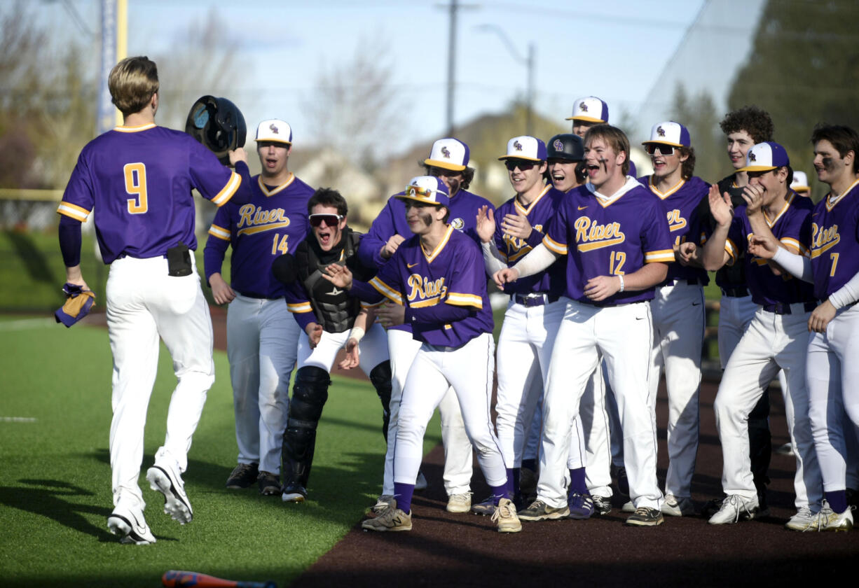 Columbia River players greet Peter Lubisich (9) after the senior hit a solo home run against Ridgefield during a 2A GSHL baseball game on Friday, March 29, 2024, at Ridgefield Outdoor Recreation Complex.
