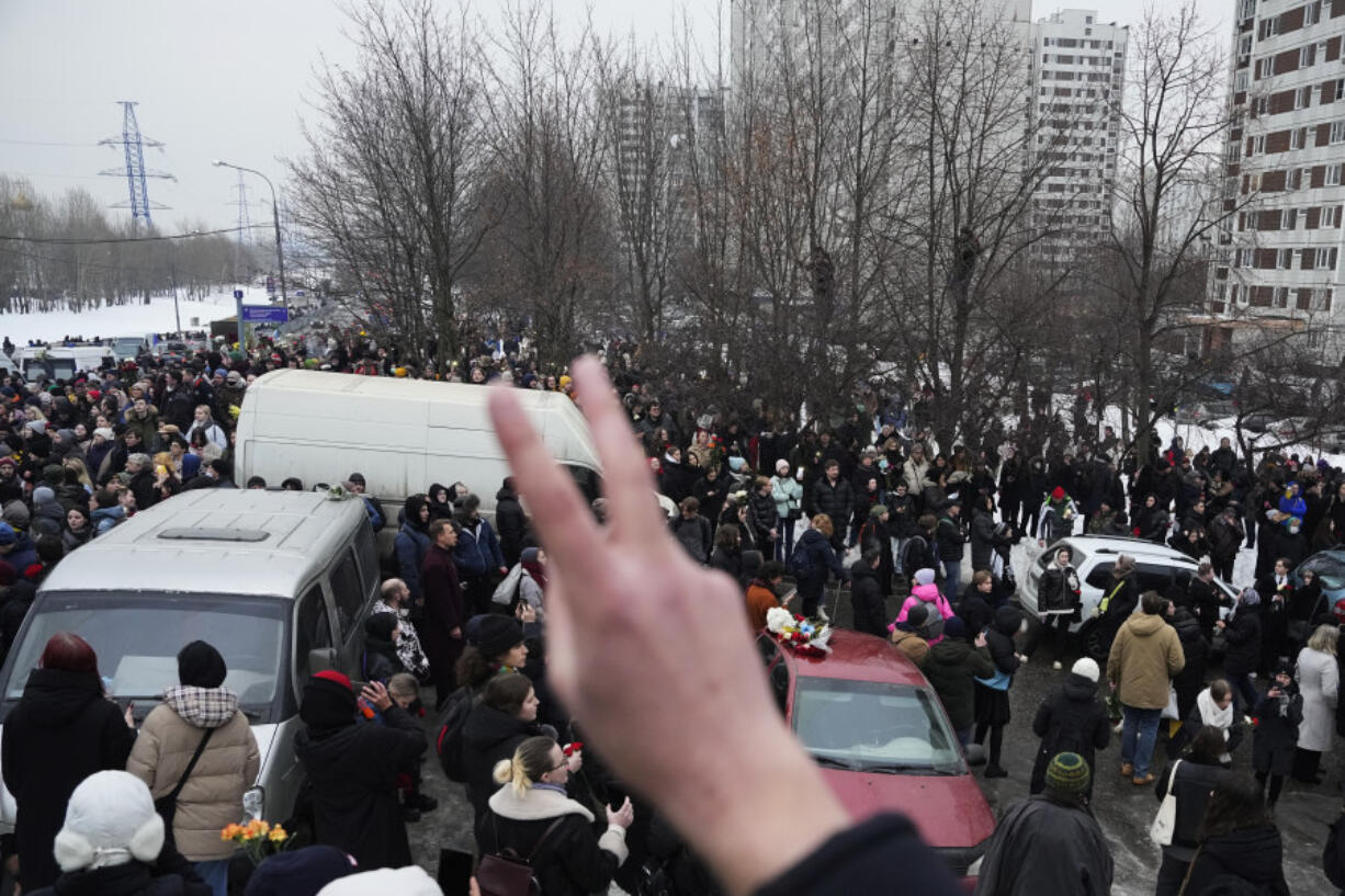 A person gestures as people walk towards the Borisovskoye Cemetery for the funeral ceremony of Russian opposition leader Alexei Navalny, in Moscow, Russia, Friday, March 1, 2024. Under a heavy police presence, thousands of people bade farewell Friday to Alexei Navalny at his funeral in Moscow after his still-unexplained death two weeks ago in an Arctic penal colony.