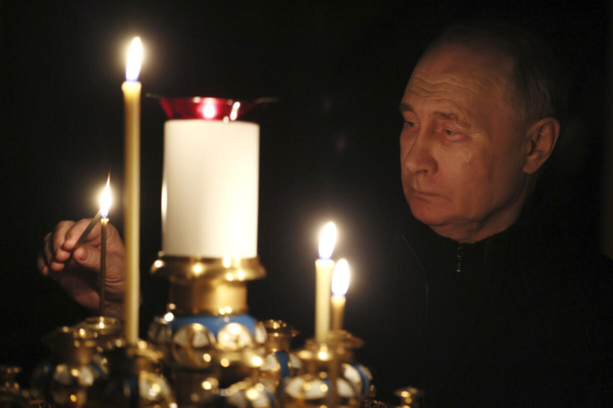 Russian President Vladimir Putin lights a candle to commemorate victims of an attack on the Crocus City Hall concert venue, on the day of national mourning, in Russia, Sunday, March 24, 2024.