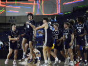 Skyview players mob Ryan Hanson (14) in celebration following Hanson's game-winning 3-pointer in Skyview's 80-77 overtime victory over Tahoma in Friday's 4A consolation semifinal.