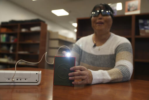 Minh Ha, assistive technology manager at the Perkins School for the Blind tries a LightSound device for the first time at the school&rsquo;s library in Watertown, Mass., on March 2, 2024. As eclipse watchers look to the skies in April 2024, new technology will allow people who are blind or visually impaired to hear and feel the celestial event.