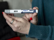 FILE - Donna Cooper holds up a dosage of Wegovy, a drug used for weight loss, at her home, March 1, 2024, in Front Royal, Va. The popular weight-loss drug Wegovy may be paid for by Medicare &mdash; as long as patients using it also have heart disease and need to reduce the risk of future heart attacks, strokes and other serious problems, federal officials said Thursday, March 21.