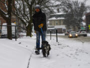 A man walks his dog down Main Street in Brattleboro, Vt., on Saturday, March 23, 2024.  New England is battling a mix of wind, rain, sleet and heavy snow across the region Saturday with more than a foot of snow expected in ski county, but mostly rain, wind and possible flooding in southern areas and along the coast.