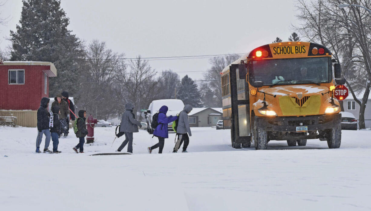 Children in winter coats line up to get into a school bus Thursday in Bismarck, N.D.