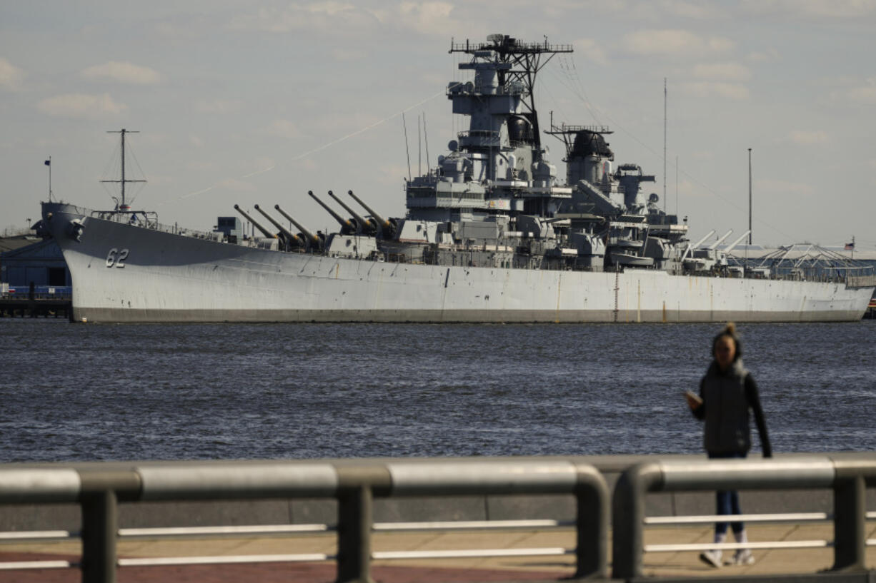 A person walks in Philadelphia across the Delaware River from the USS New Jersey in Camden, N.J., Tuesday, March 19, 2024. The battleship is scheduled to move from its dock in Camden on March 21, when it will head to the Philadelphia Navy Yard for extensive maintenance work. The USS New Jersey is scheduled to move from its dock in Camden on Thursday,  March 21, 2024, when it will head to the Philadelphia Navy Yard for extensive maintenance work.